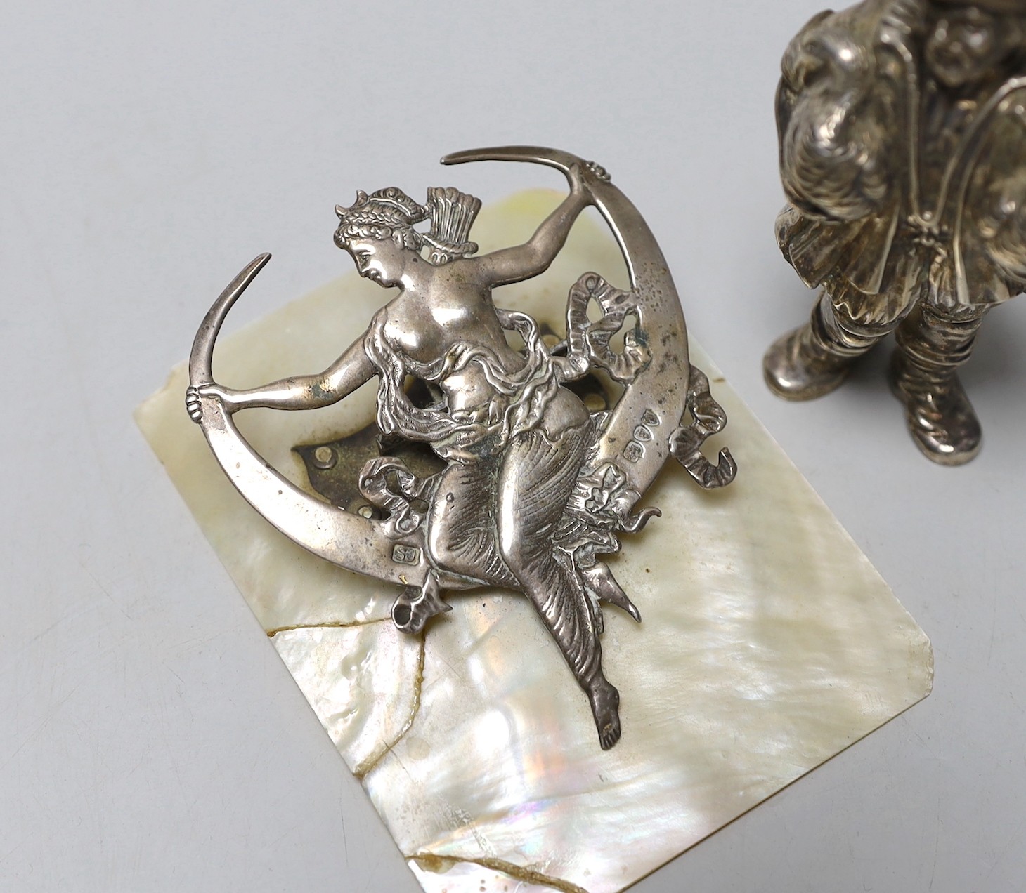 A late Victorian silver mounted mother of pearl letter clip, Samuel Jacob, London, 1893, 10.8cm (a,f,) and a late 19th century Hanau white metal figural pepperette, 10cm.